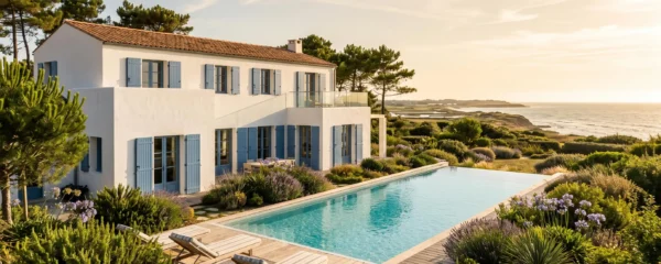 White luxury villa with infinity pool on Île de Ré, featuring traditional blue shutters and terracotta roof, surrounded by coastal garden vegetation under warm natural sunlight